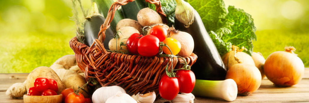Basket of colorful vegetables on a wooden table outside
