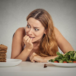 Woman struggling to choose between cookies and salad