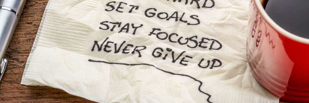 Notes about goals for better health written on a napkin next to a mug of coffee