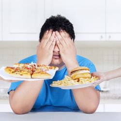 Young man covering his eyes to unhealthy food