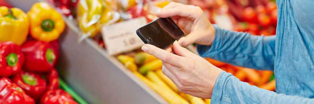 Woman using her phone to help her shop in the produce aisle