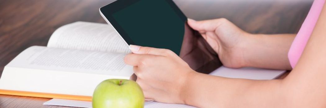 close up of a woman with an apple reading something on a tablet
