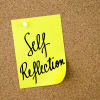 yellow self reflection post it note pinned to a cork board